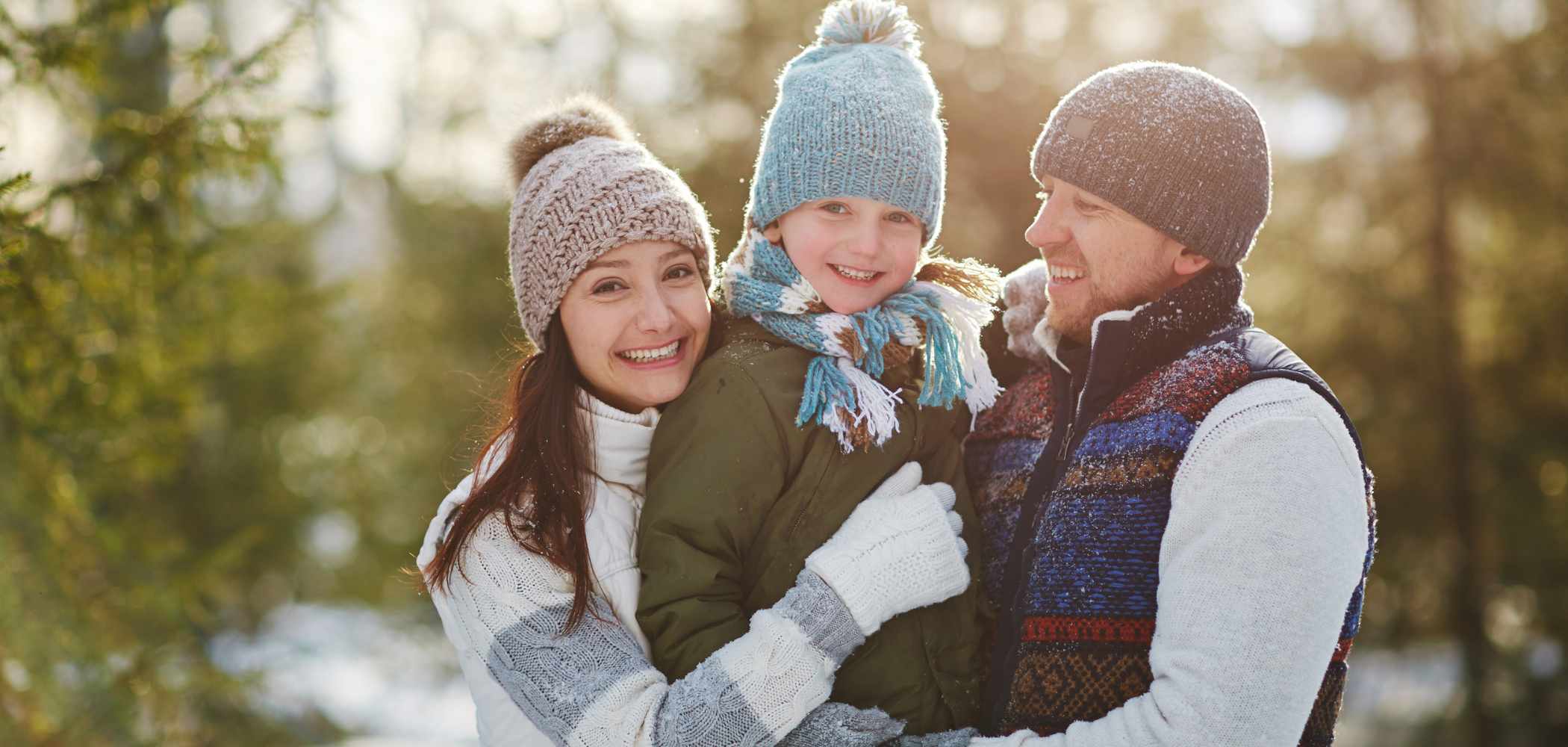 A family photo of two parents and their child, wearing winter jackets and accessories.